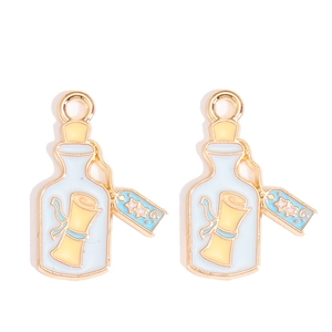 Detailed macro view of blue enamel message bottle charms with gold-plated alloy finish