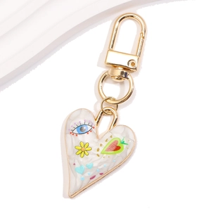 Detail of heart-shaped keychain with marble texture and evil eye print on golden clip
