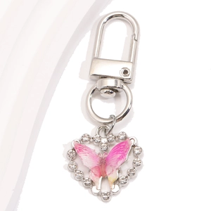 Détail d'un porte-clés en forme de cœur avec papillon rose dégradé et cristaux étincelants