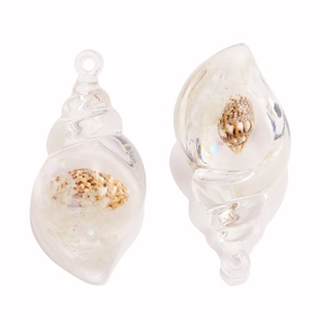 Macro detail of acrylic conch pendants with mini shells and sand inside for DIY jewelry
