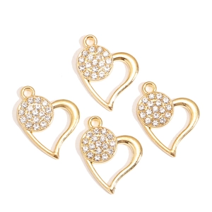Close-up of four gold hollow heart pendants with inlaid white rhinestones for DIY jewelry