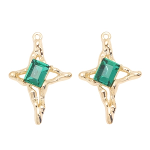 Détail macro de pendentifs croix dorés avec cristaux verts à coupe émeraude