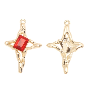Détail d'un pendentif croix Y2K en alliage doré avec un cristal rouge rectangulaire facetté