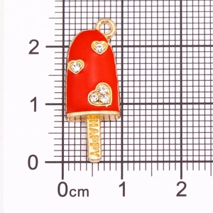 Detail eines roten Emaille-Eis-Anhängers mit Herz-Strass auf dem Messraster
