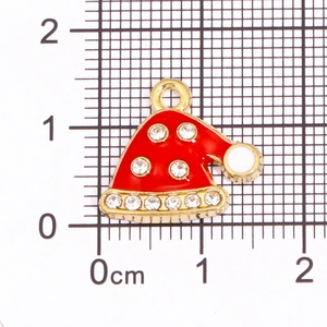 Detail eines roten Emaille-Weihnachtshutes mit Strasssteinen und Lineal zur Größenmessung