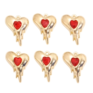 Détail de six breloques cœur en métal doré et pierres rouges pour bijoux faits main