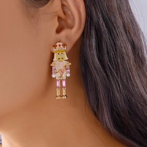 Détail des boucles d'oreilles casse-noisette avec émail rose, strass et perles sur mannequin