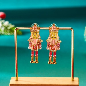 Détail de boucles d'oreilles casse-noisette avec strass roses et émail sur un support doré