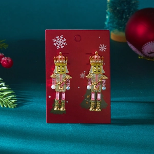 Détail de boucles d'oreilles casse-noisette avec cristaux sur carte de Noël rouge
