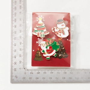 Details von Weihnachts-Emaille-Pins mit Weihnachtsmann und Baum auf roter Karte