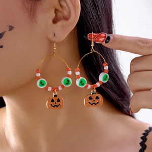 Dettaglio di orecchini di Halloween con ciondolo a zucca e perline colorate