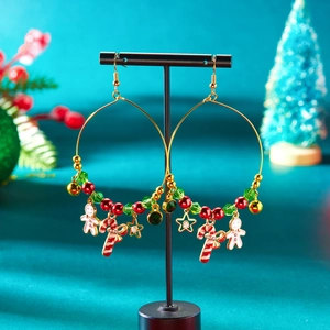 Nahaufnahme von goldenen Weihnachts-Ohrringen mit Lebkuchenmann- und Zuckerstangen-Anhängern