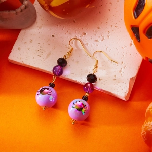 Dettaglio di orecchini di Halloween con perle viola e motivo a ragno cartoon