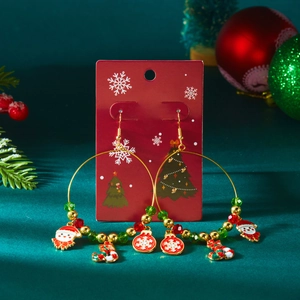 Details von Weihnachts-Ohrringen mit Nikolaus- und Schneeflocken-Anhängern auf roter Karte