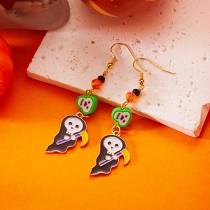 Dettaglio macro di orecchini di Halloween con teschio e perline arancioni su sfondo a tema