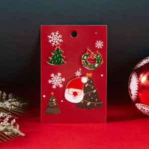Drei Weihnachts-Emaille-Broschen mit Tannenbaum und Nikolaus auf festlicher Karte