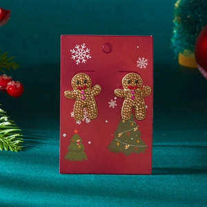 Gros plan de boucles d'oreilles bonhomme de pain d'épices avec cristaux sur carte festive