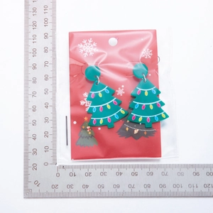 Detail van acryl kerstboom oorbellen met kleurrijke stippen en een liniaal