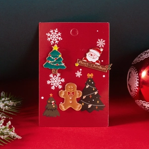 Detailansicht eines 3er-Sets Weihnachts-Emaille-Broschen auf festlicher roter Karte