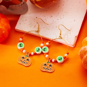 Dettaglio di orecchini a cerchio di Halloween con zucche e perline su sfondo arancione