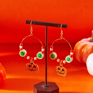 Dettaglio degli orecchini di Halloween con ciondoli a zucca e alieno su espositore nero