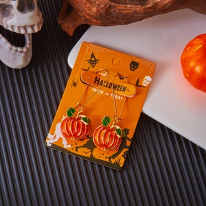 Dettaglio di orecchini a zucca arancione con foglia verde su cartoncino Halloween