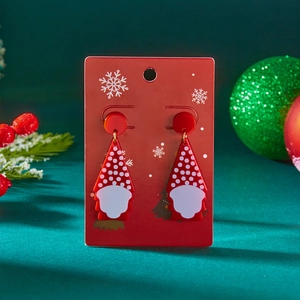 Detailopname van kerstman-kabouter oorbellen van acryl op een feestelijke cadeaukaart