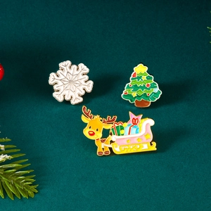 Nahaufnahme des Emaille-Weihnachtsbrosche-Sets mit Schneeflocke, Baum und Rentier-Motiv