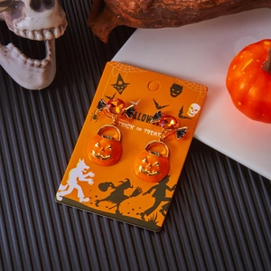 Orecchini a zucca di Halloween con fiocchi neri presentati su cartoncino a tema