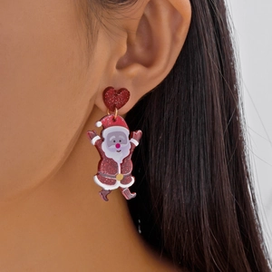 Macro shot of glitter red heart stud and Santa Claus acrylic earrings worn on ear