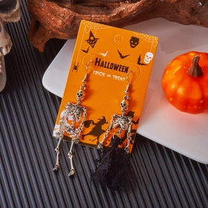 Dettaglio di orecchini a teschio argento con nappa nera su carta a tema Halloween