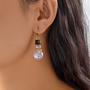Detailed close-up of a snowman pearl earring with a black hat and gold crystal scarf