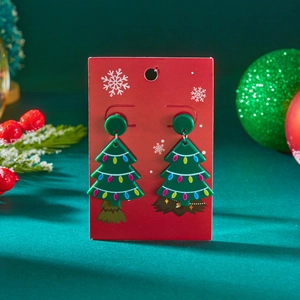 Kerstboom acryl oorbellen met feestelijke patronen op een rode sneeuwvlok kaart