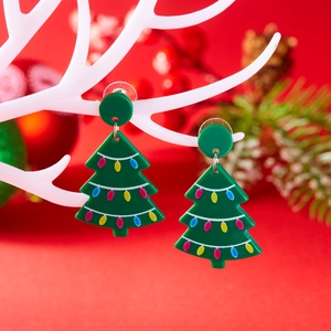 Detailopname van groene acryl kerstboom oorbellen op een witte sieradenhouder