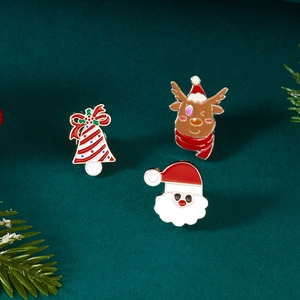Detail der Weihnachts-Emaille-Pins mit Weihnachtsmann, Rentier und Glocke auf grünem Grund