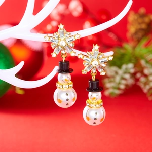 Macro detail of Christmas snowman drop earrings with sparkling rhinestones and white pearls