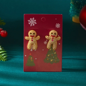 Boucles d'oreilles bonhomme en pain d'épices avec perles sur fond rouge festif