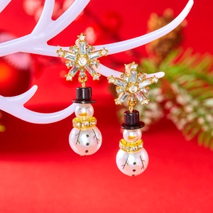 Detail of Christmas snowman earrings with rhinestone snowflakes on a white reindeer prop