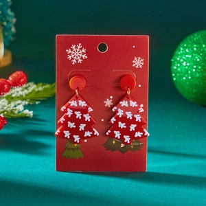 Detail van rode acryl kerstboom oorbellen met sneeuwvlokpatronen op een fluwelen achtergrond