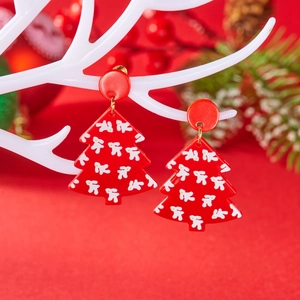 Detail van rode kerstboom oorbellen van acryl met witte sneeuwvlokpatronen op een standaard