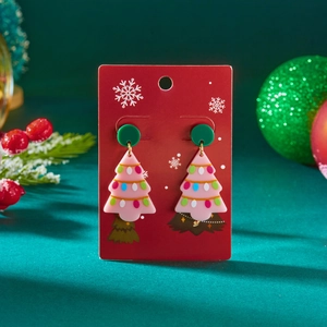 Macro detail van feestelijke roze acryl kerstboom oorbellen op een cadeaukaart