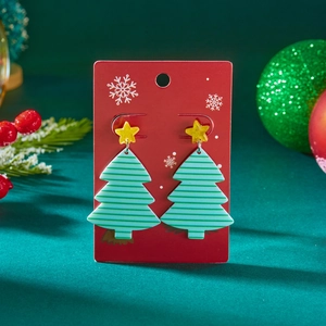 Detail van acryl kerstboom oorbellen met sterren op een rode decoratieve display kaart