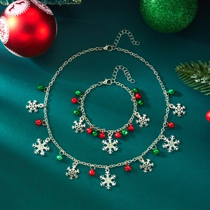 Christmas jewelry set with silver snowflake pendants and colorful bells on green background