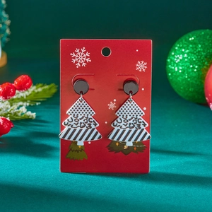 Detailweergave van acryl kerstboom oorbellen met patroon op een rode displaykaart