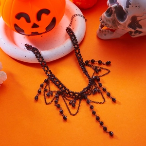 Detail of gothic multi-layer necklace with black beads and fringe on Halloween orange background