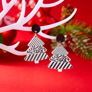 Detail van acryl kerstboom oorbellen met luipaardprint tegen een rode feestelijke achtergrond