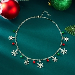 Detail of Christmas necklace with rhinestone snowflakes and colorful metal bells on green cloth
