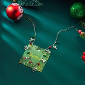 Christmas necklace detail with silver snowflakes and bells on festive green card