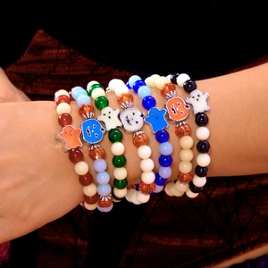 Close-up of Halloween beaded bracelets with pumpkin and ghost charms on a model's wrist