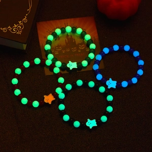 Luminous Halloween beaded bracelets with ghost pendants glowing in dark festive setting